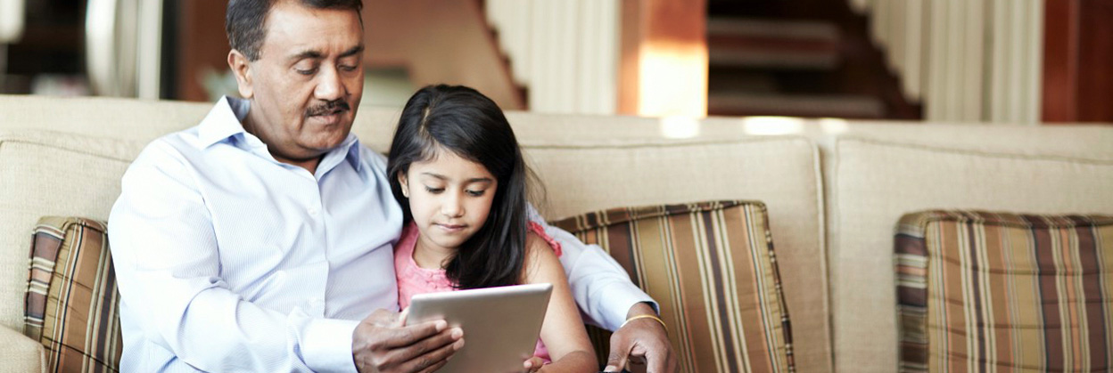 Grandfather and granddaughter sitting on sofa